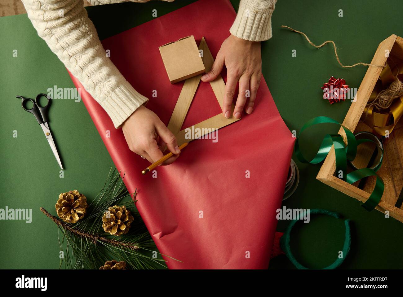Woman using ruler to draw on gift paper, calculating amount of ...