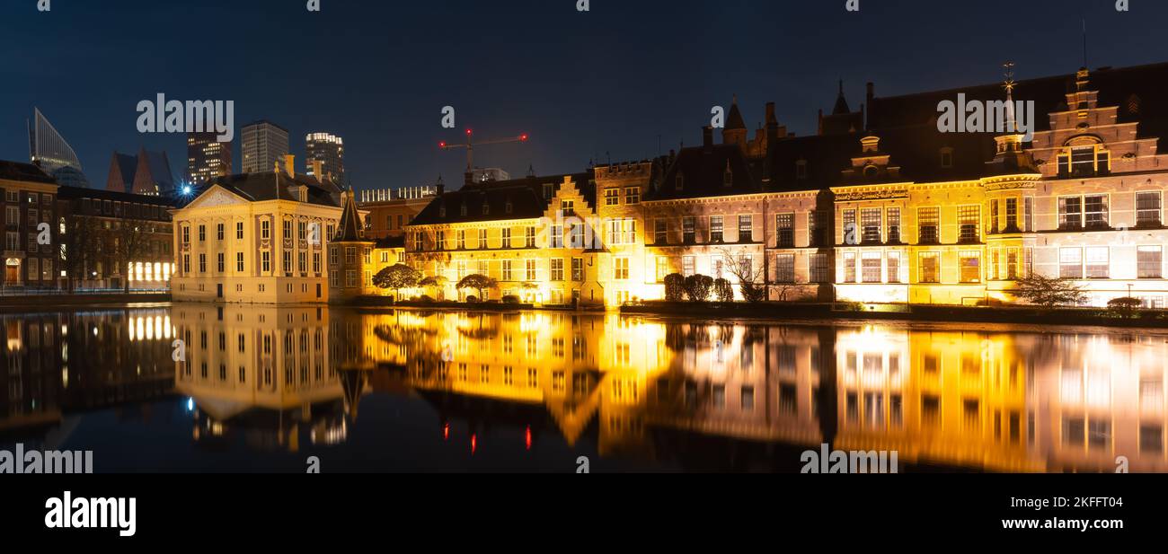 Panorama of The Hague at night, view of historical complex Binnenhof with famous Mauritshuis museum, Hofvijver lake and small octagonal building known Stock Photo