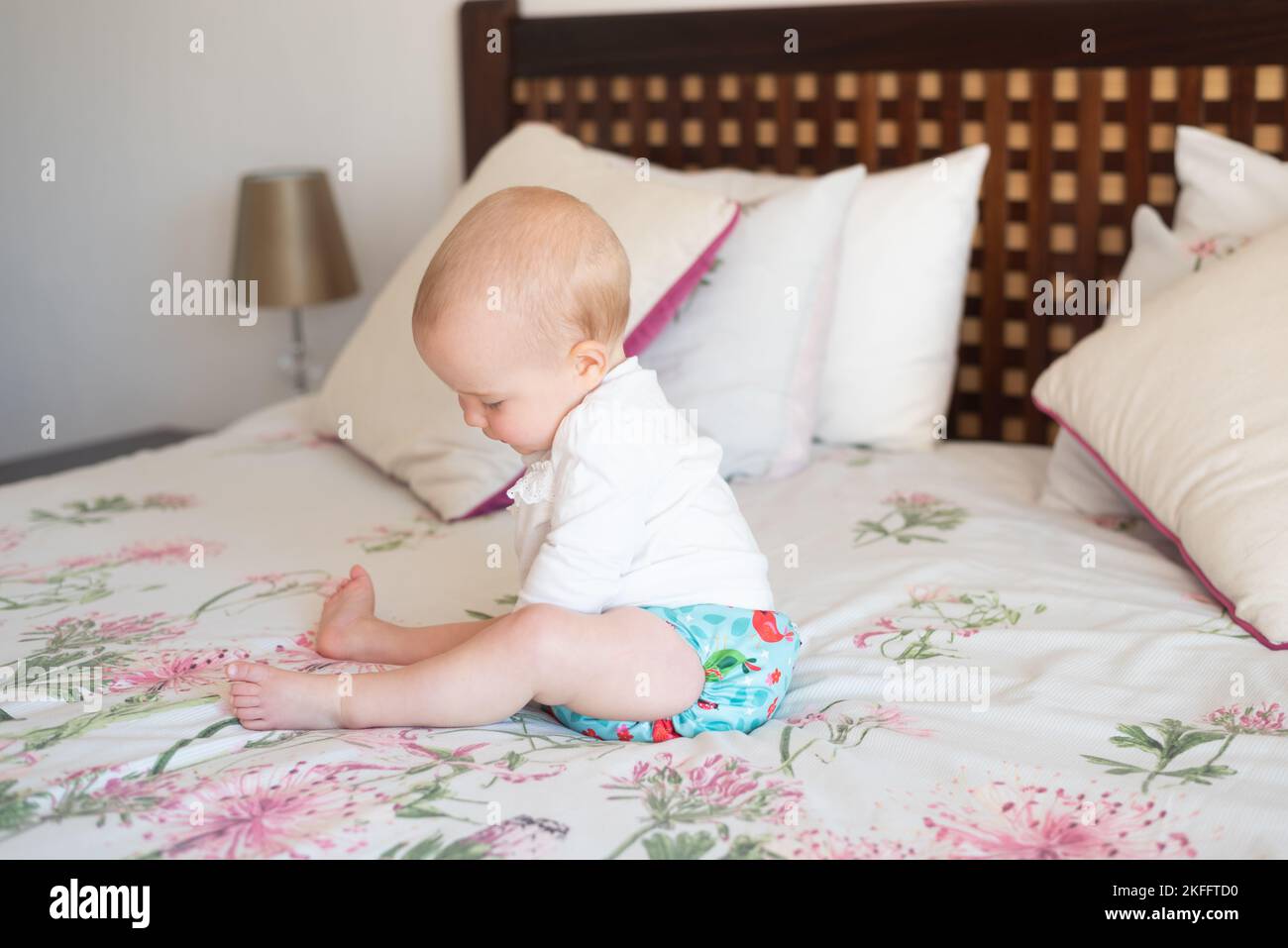 A happy baby girl learning how to sit. She is wearing a modern, reusable cloth diaper Stock