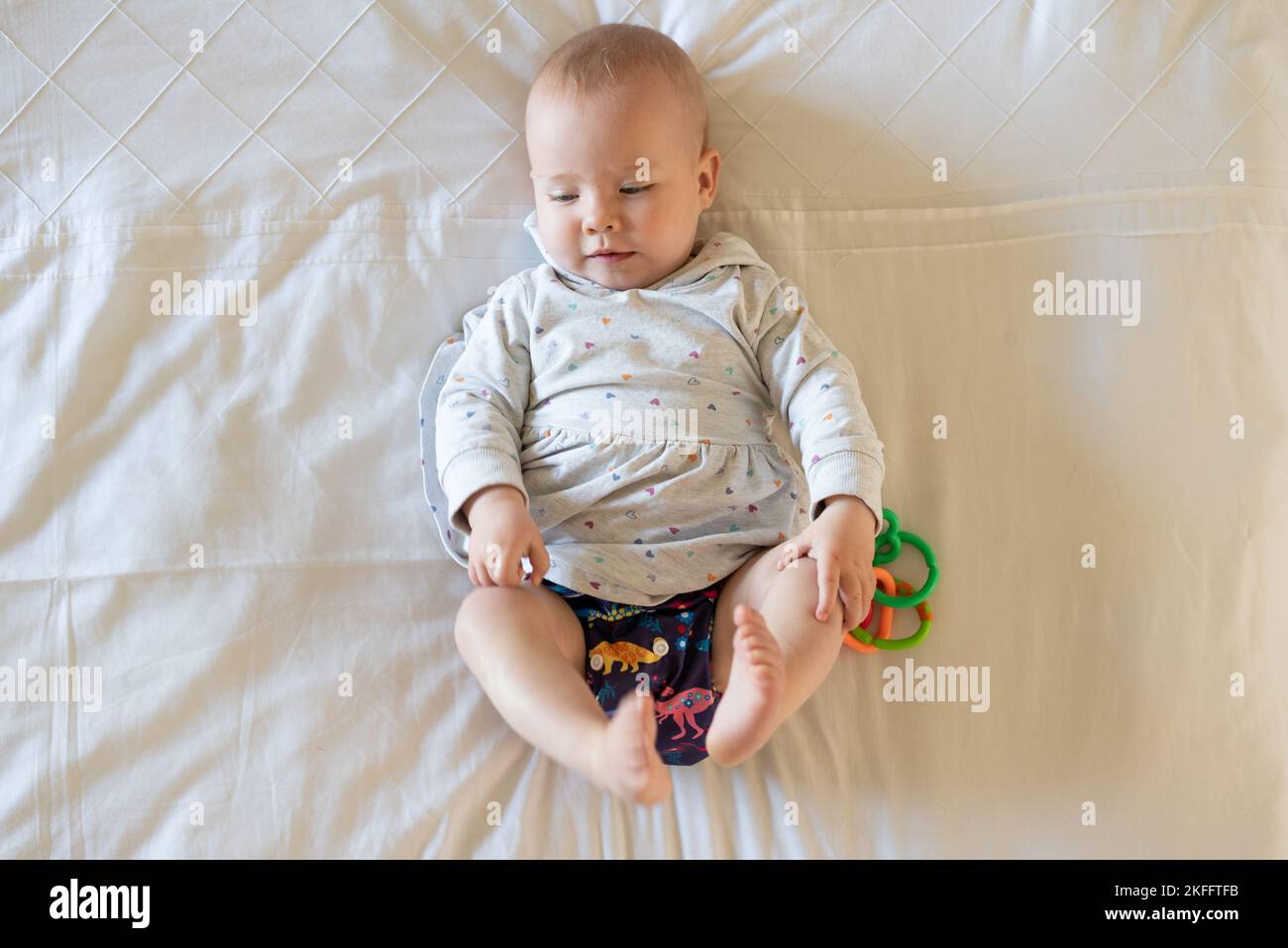 happy-baby-girl-lying-on-her-back-on-a-bed-she-is-wearing-a-modern