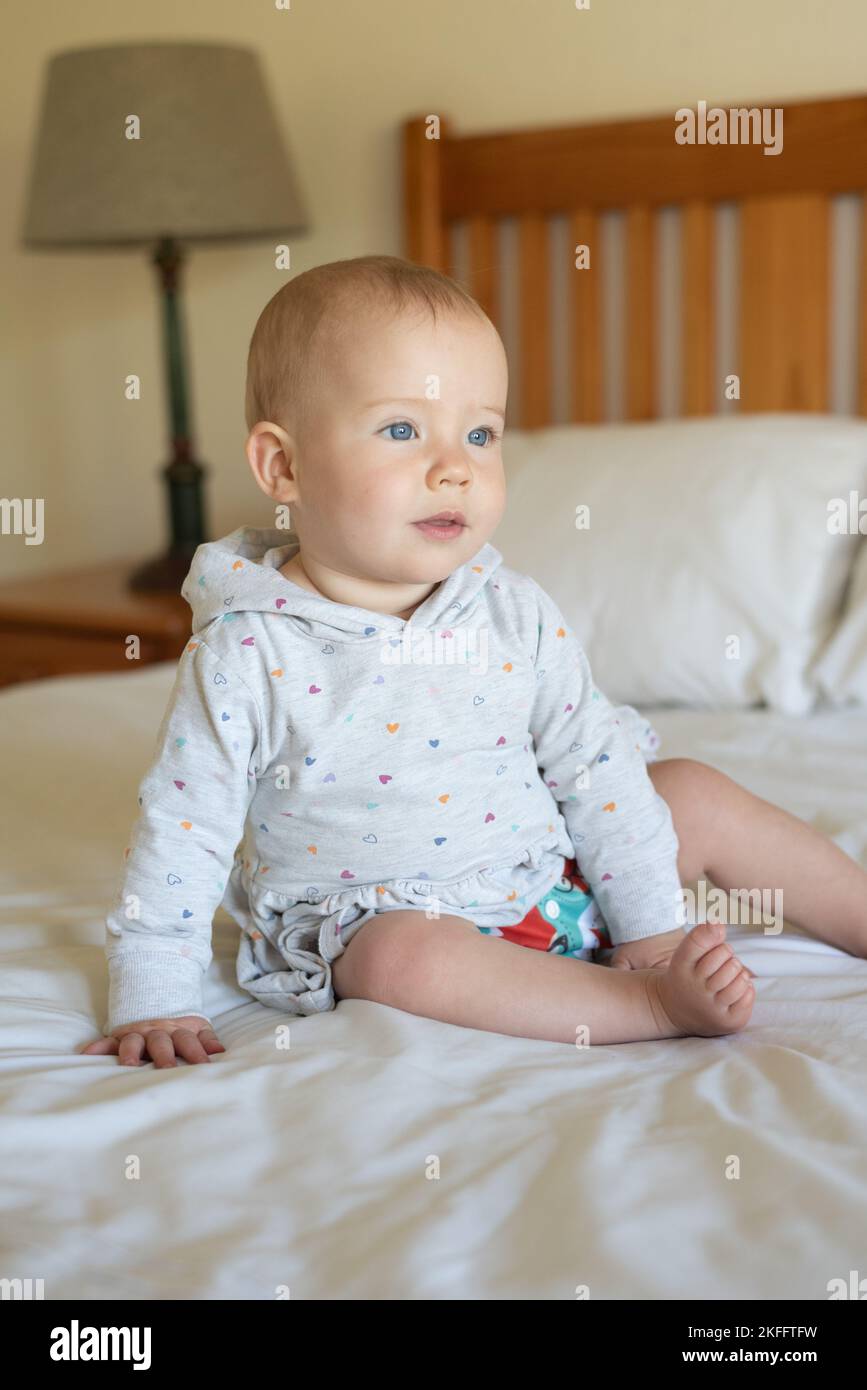 A happy baby girl learning how to sit. She is wearing a modern