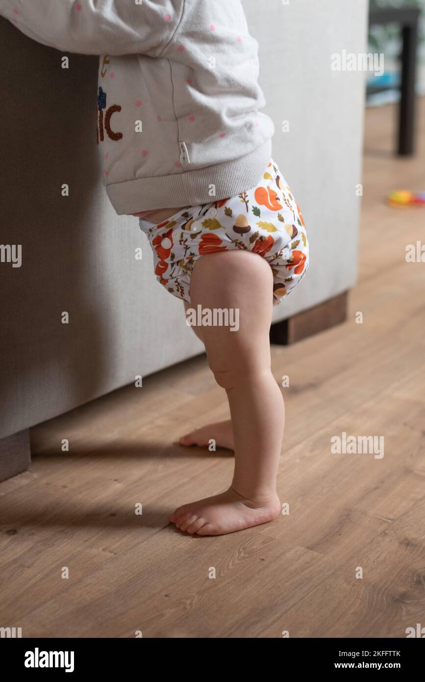 A baby girl learning how to stand up. She is wearing a modern, reusable