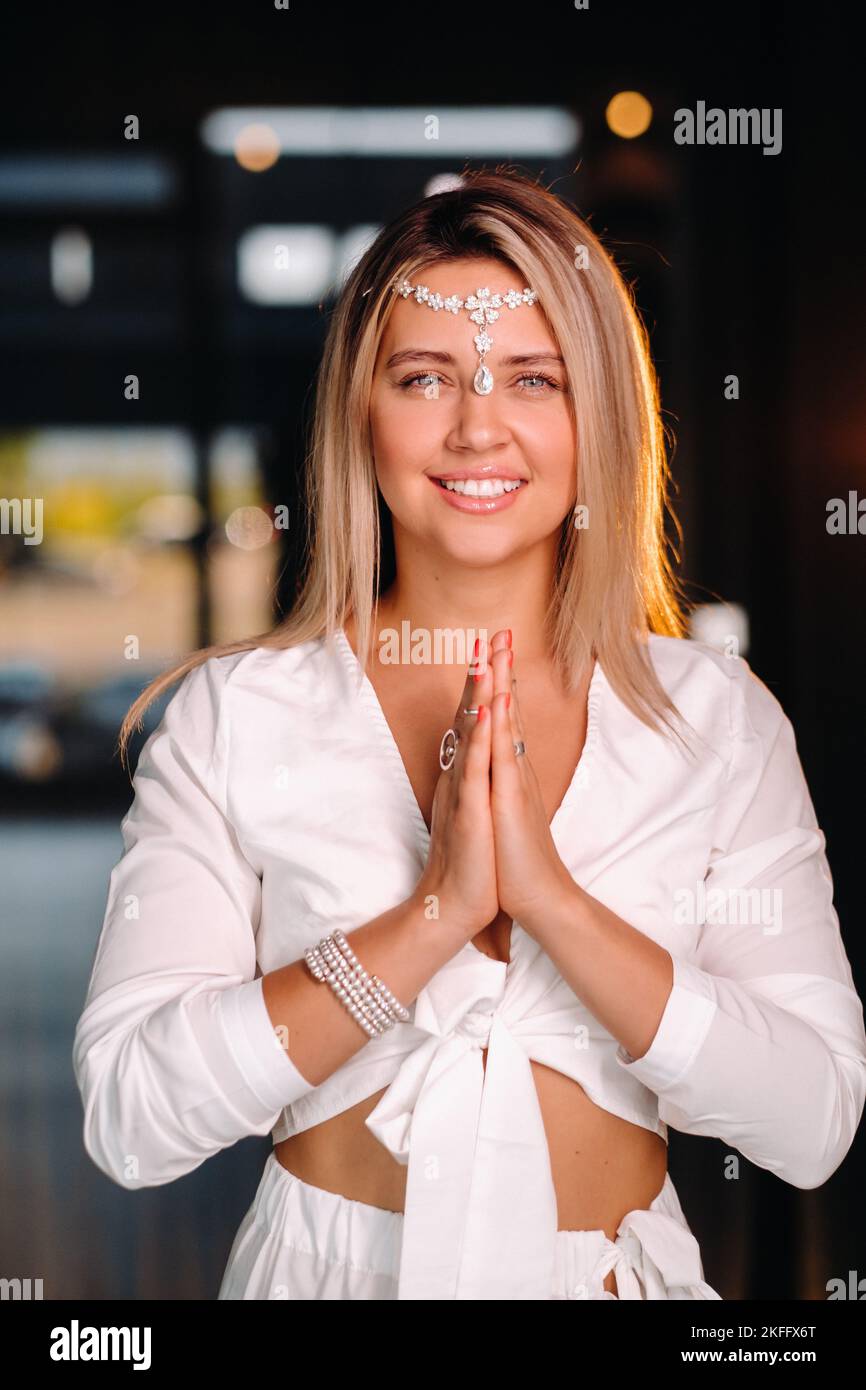 Portrait of a smiling girl in a white dress with her palms clasped in front of her Stock Photo
