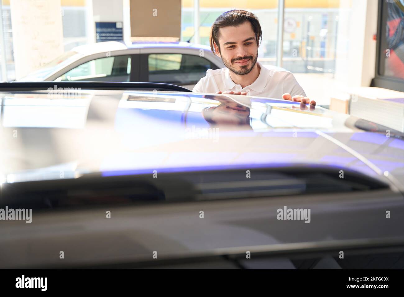 Smiling young potential buyer inspecting car exterior Stock Photo