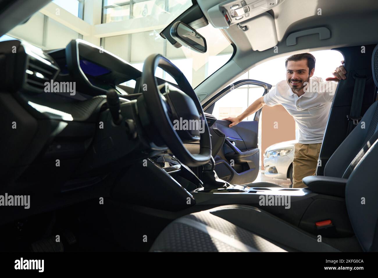 Happy potential buyer admiring new automobile interior Stock Photo