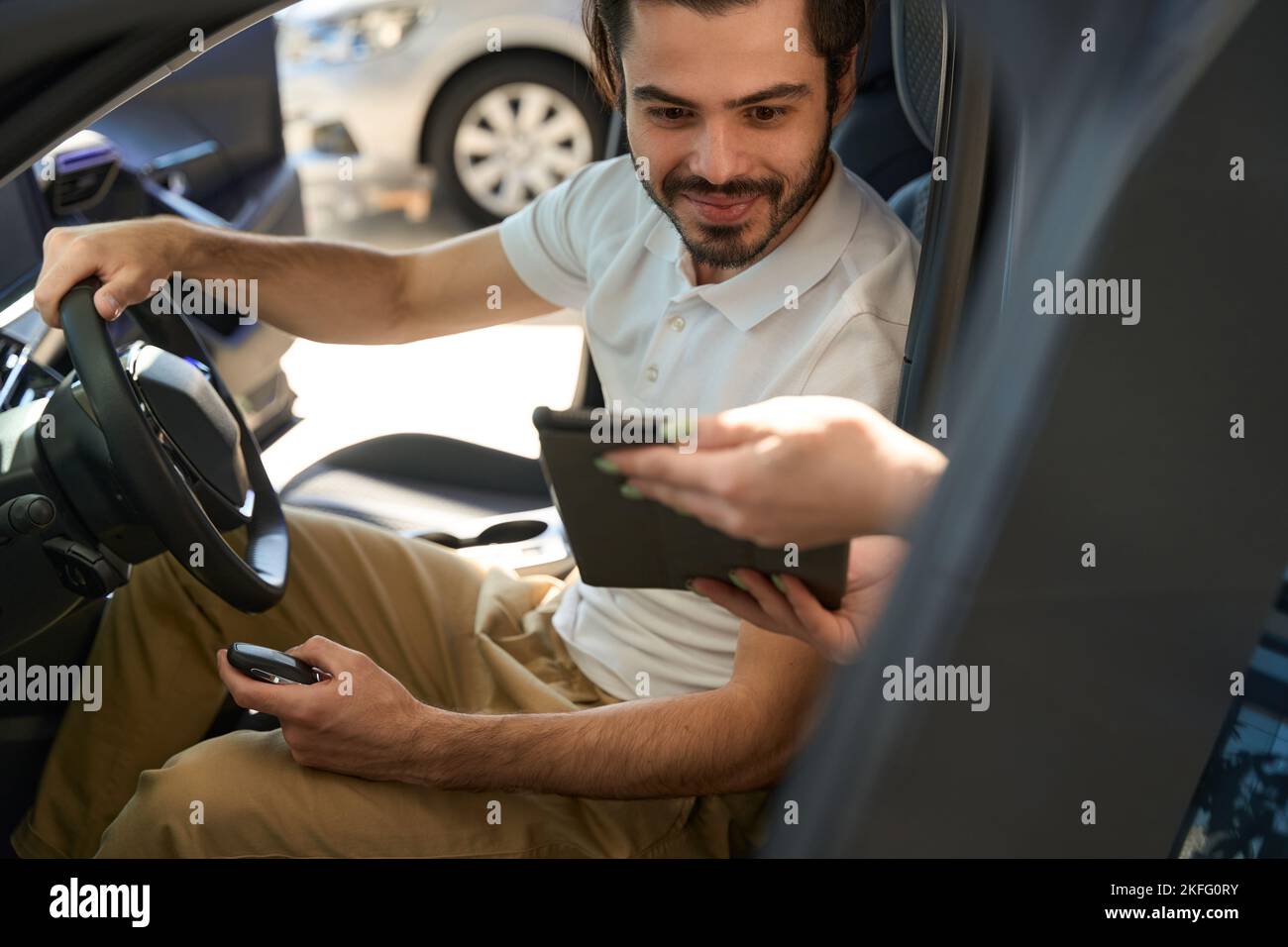 Happy automotive buyer reading digital car purchase agreement Stock Photo