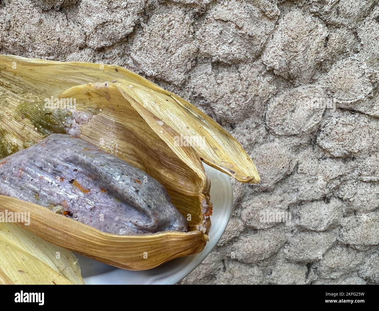 Tamale made from blue corn with squash blossoms wrapped in a corn husk