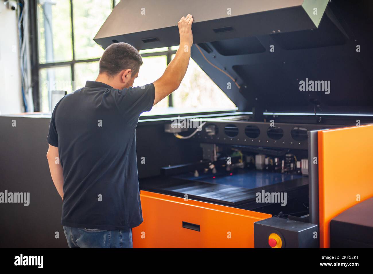Professional worker with modern big offset printing machine in print