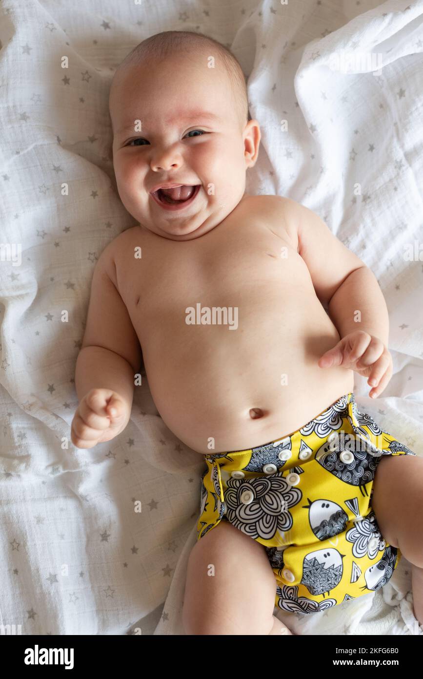 A happy, content baby girl lying on her back. She is wearing a modern