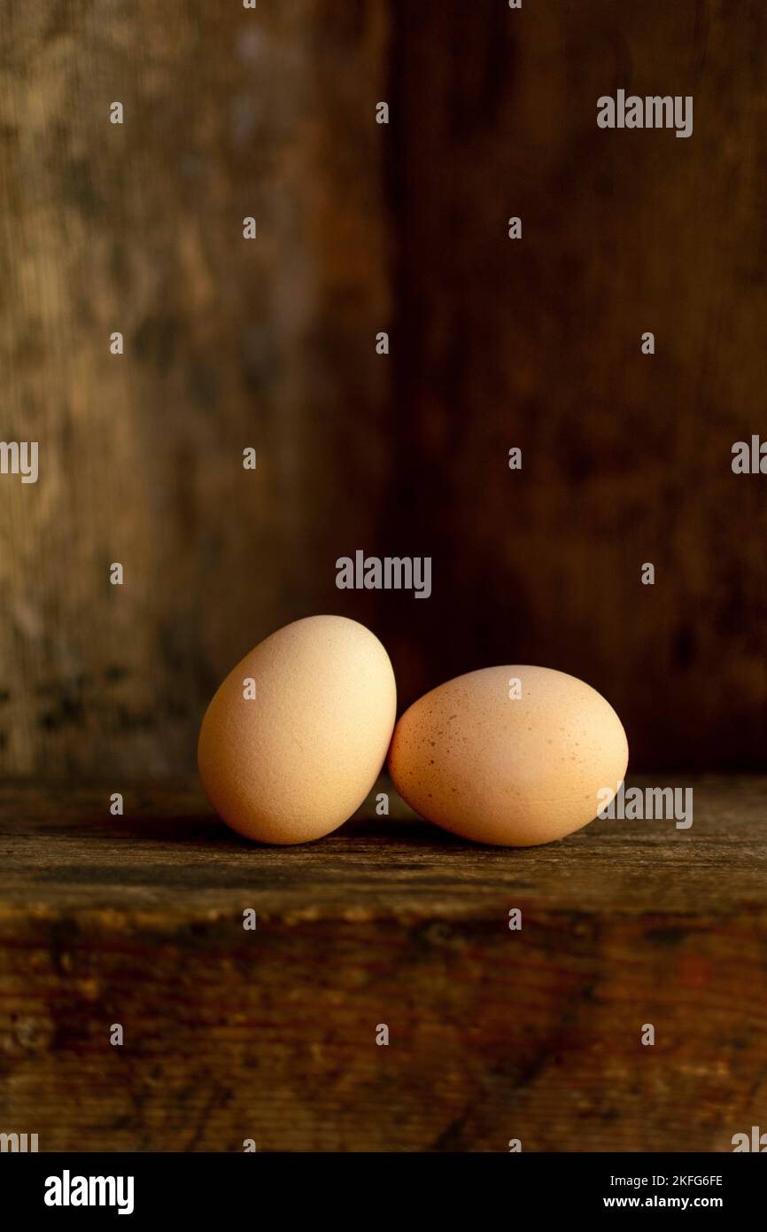 Vertical shot of two eggs with an old wooden background Stock Photo