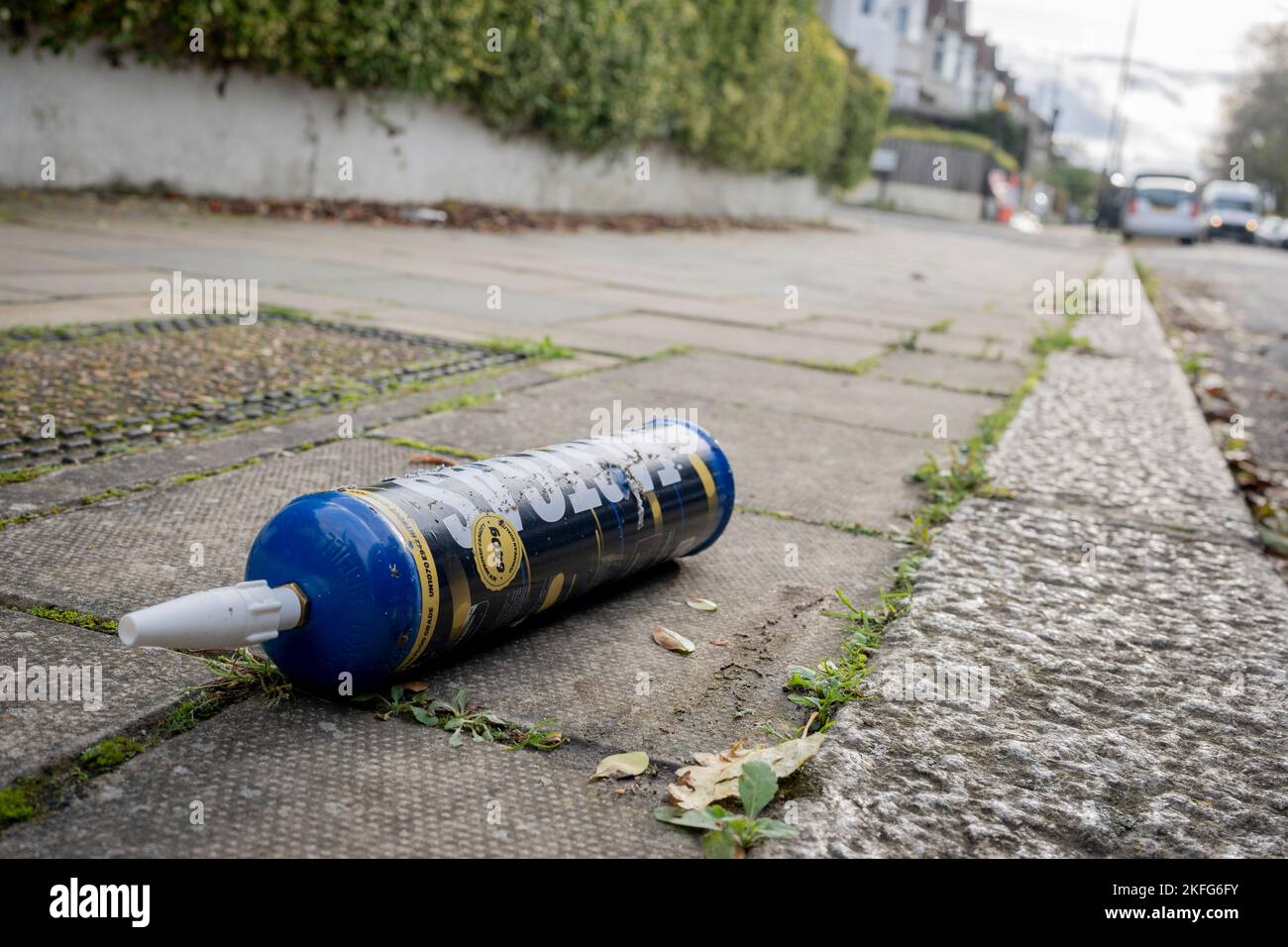 A Fast Gas nitrous oxide cylinder lies on the pavement of a surburban