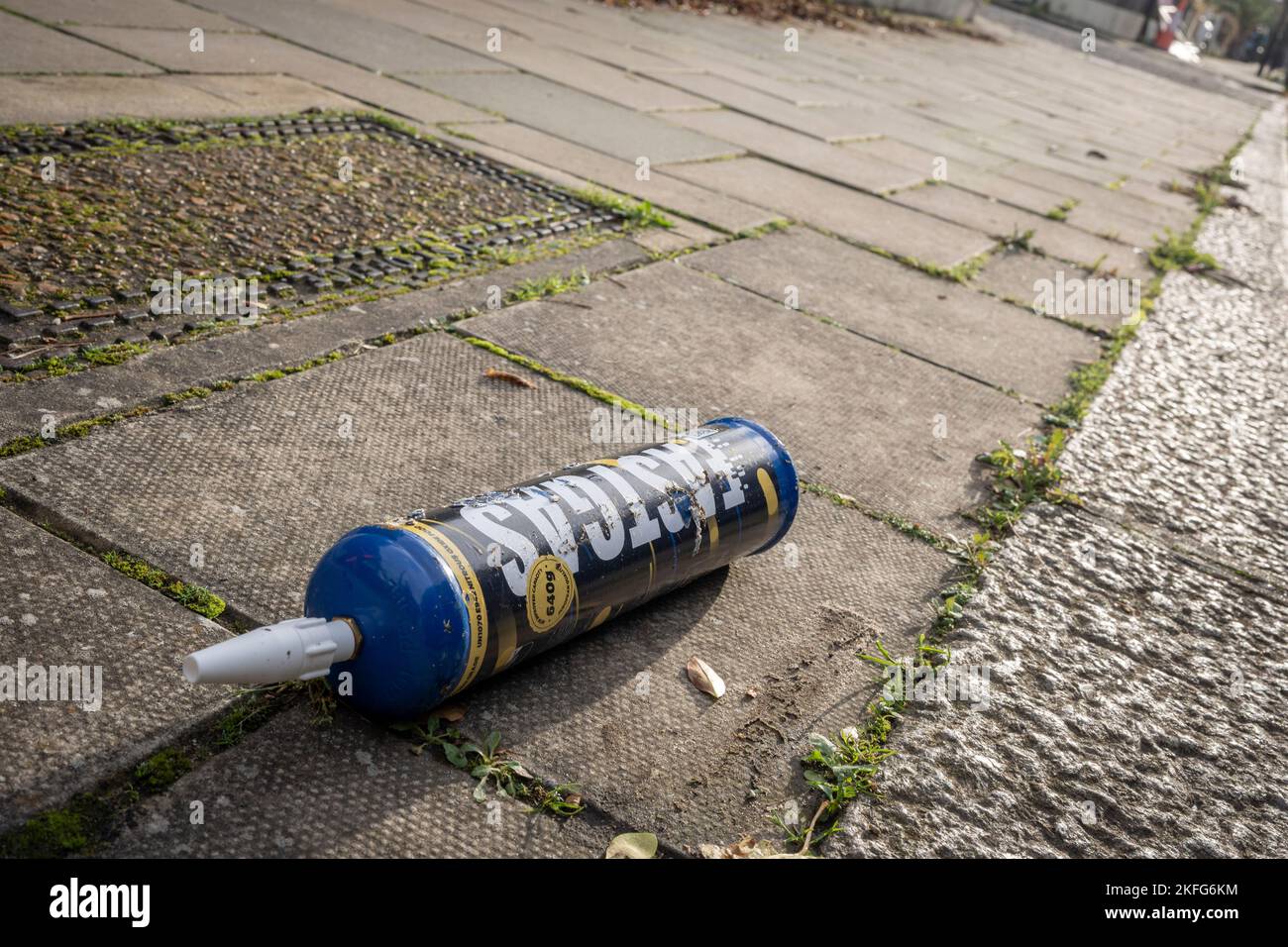 A Fast Gas nitrous oxide cylinder lies on the pavement of a surburban south London street, on 17th November 2022, in London, England. Fast Gas state that their nitrous oxide disposable cylinders have a capacity of 640 grams of nitrous oxide with a purity level of 99%. Nitrous oxide is illegal under the 2016 Psychoactive Substances Act but laughing gas is now the fourth most used drug in the UK, according to the Global Drug Survey 2015. (Photo by Richard Baker / In Pictures via Getty Images) Stock Photo