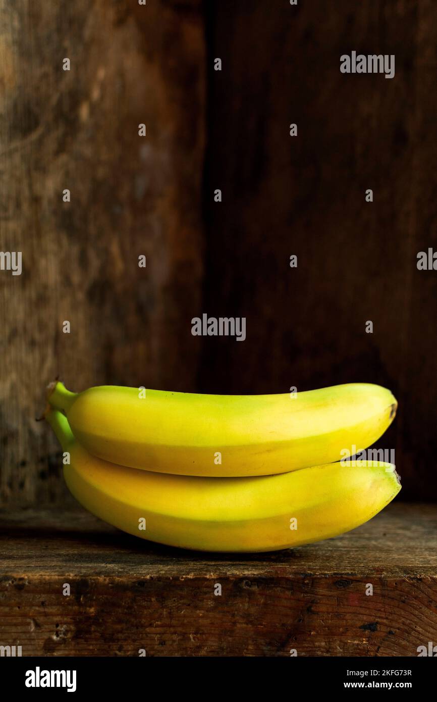 Vertical shot of two bananas with an old wooden background Stock Photo