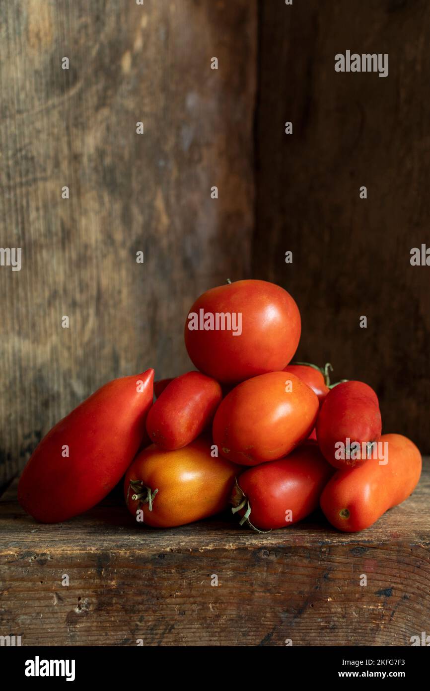 Vertical shot of fresh garden tomatoes with an old wooden background Stock Photo
