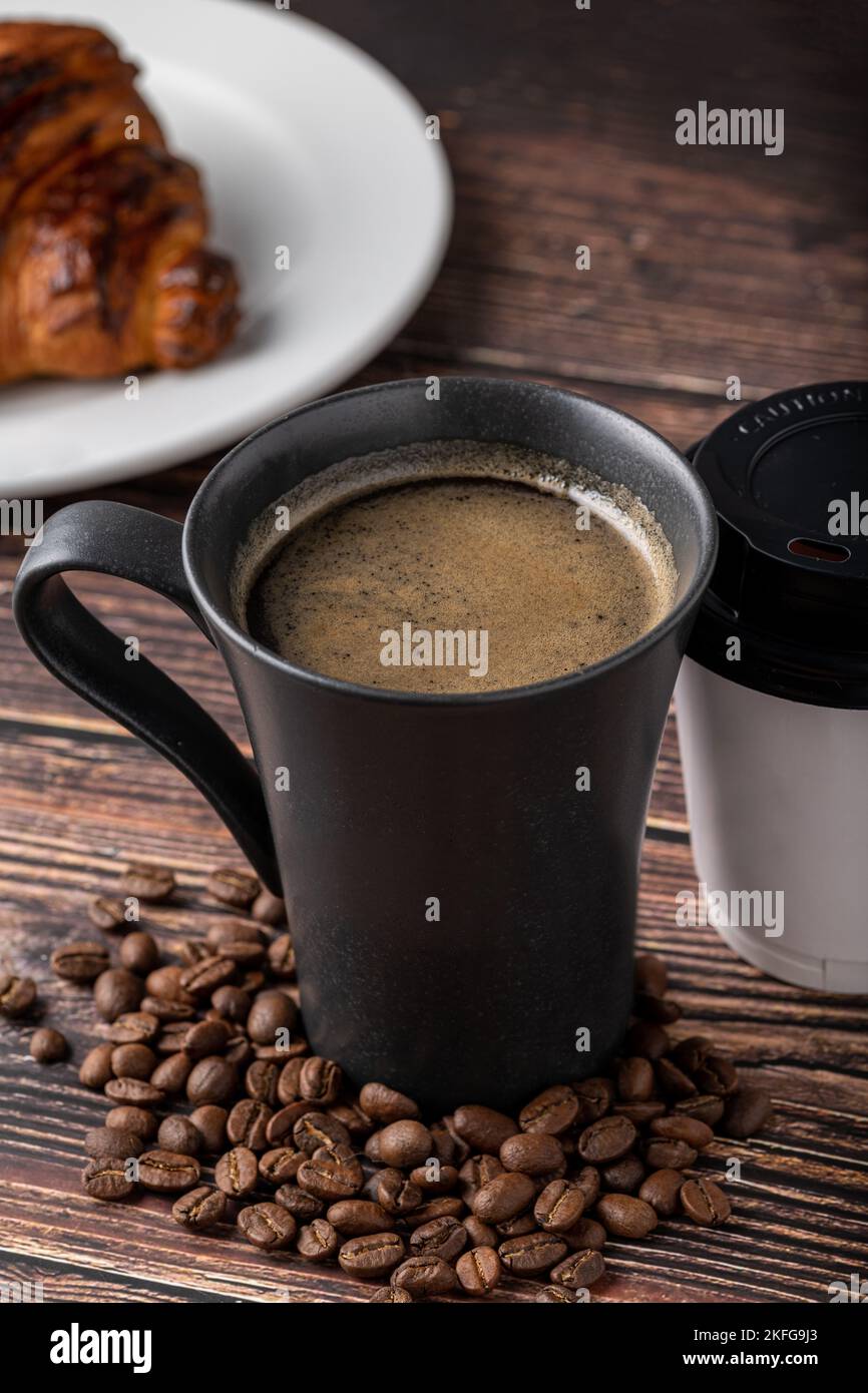 Relaxing americano coffee in black porcelain cup and take away cup on wooden table Stock Photo