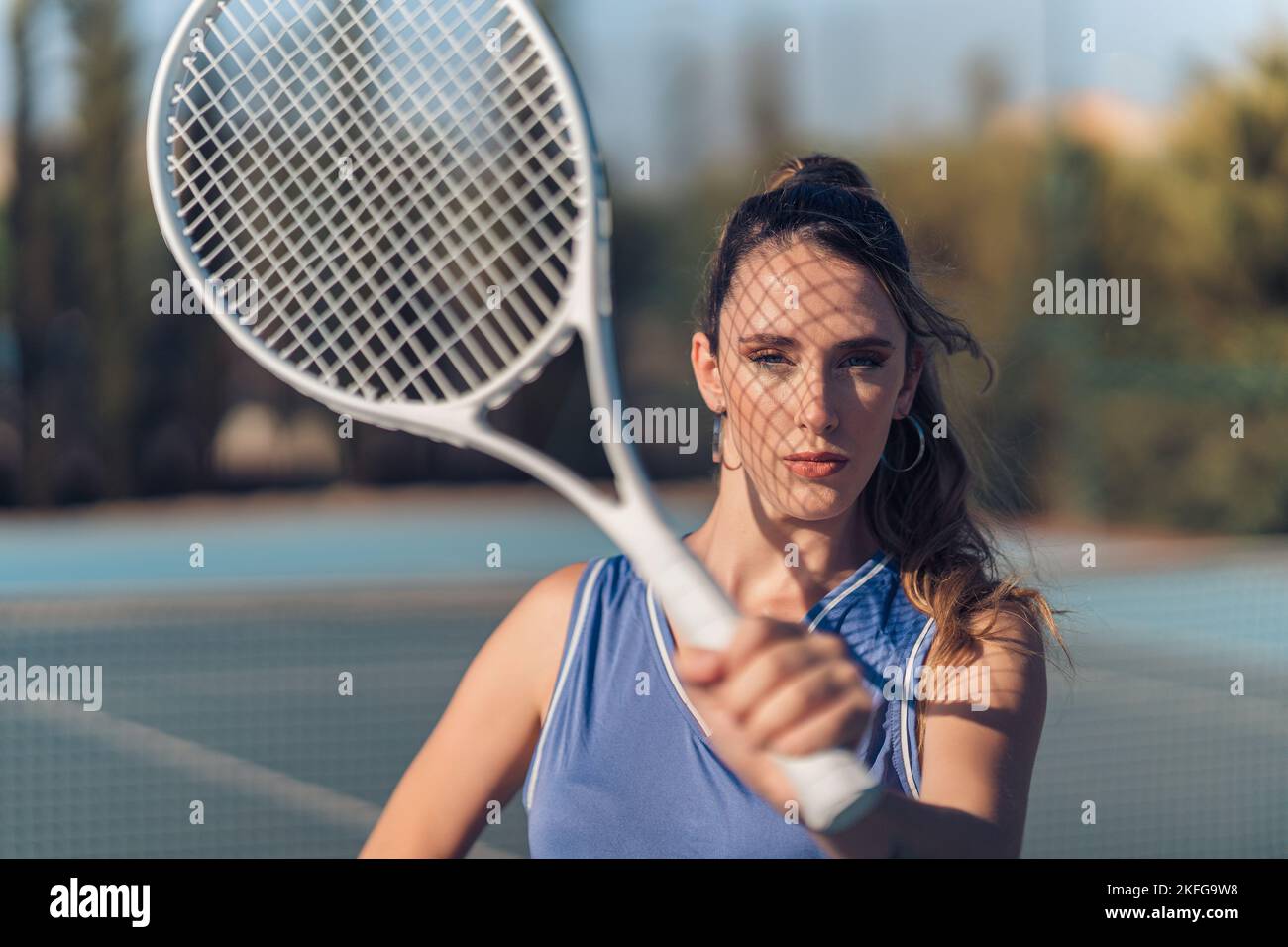 Photo Poses With Racket A young attractive fit caucasian female posing with a tennis racket on ...