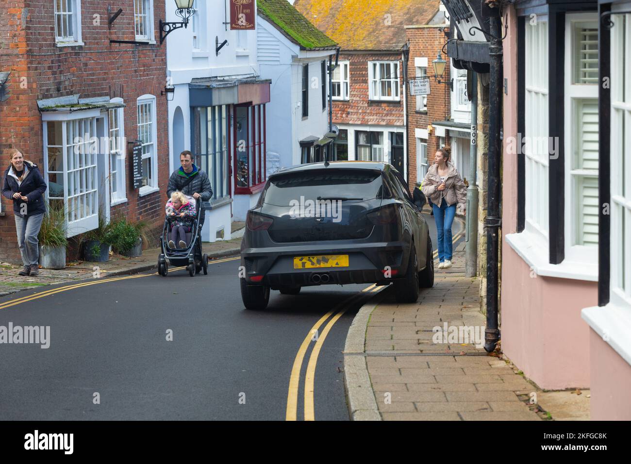 Inconsiderate driver parking on double yellow lines and on the pavement and pushchair pedestrians on road, Rye, East Sussex, uk Stock Photo