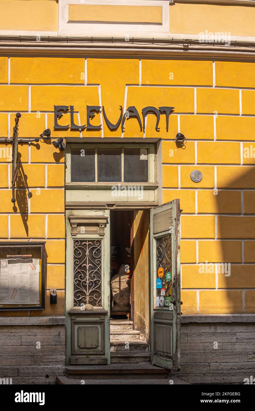 Estonia, Tallinn - July 21, 2022: Front door set in yellow stone facade of Elevant Indian vegetarian restaurant. Open door at Vene street Stock Photo