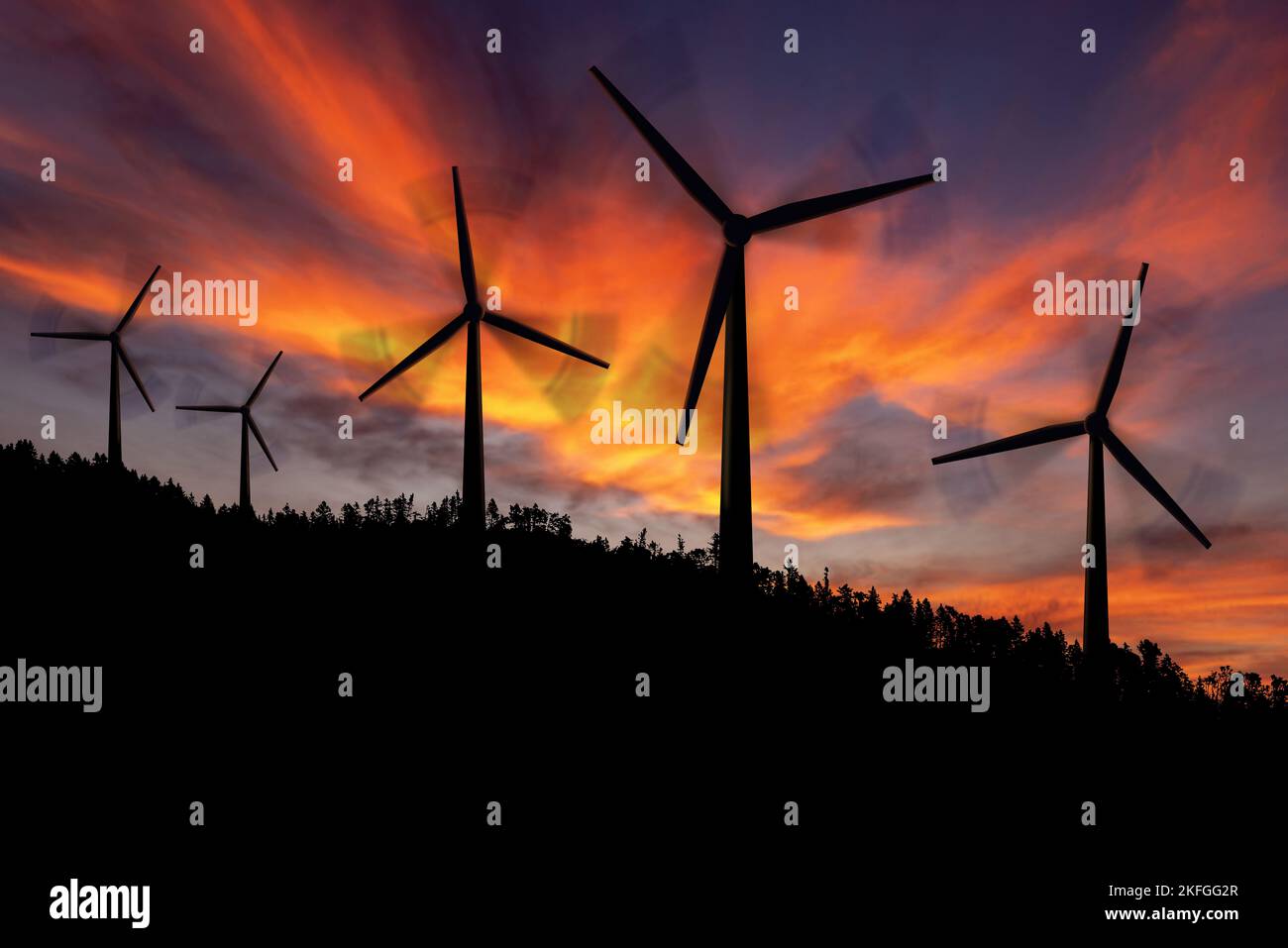 Silhouettes of a group of wind turbines and a pine forest in mountain ...