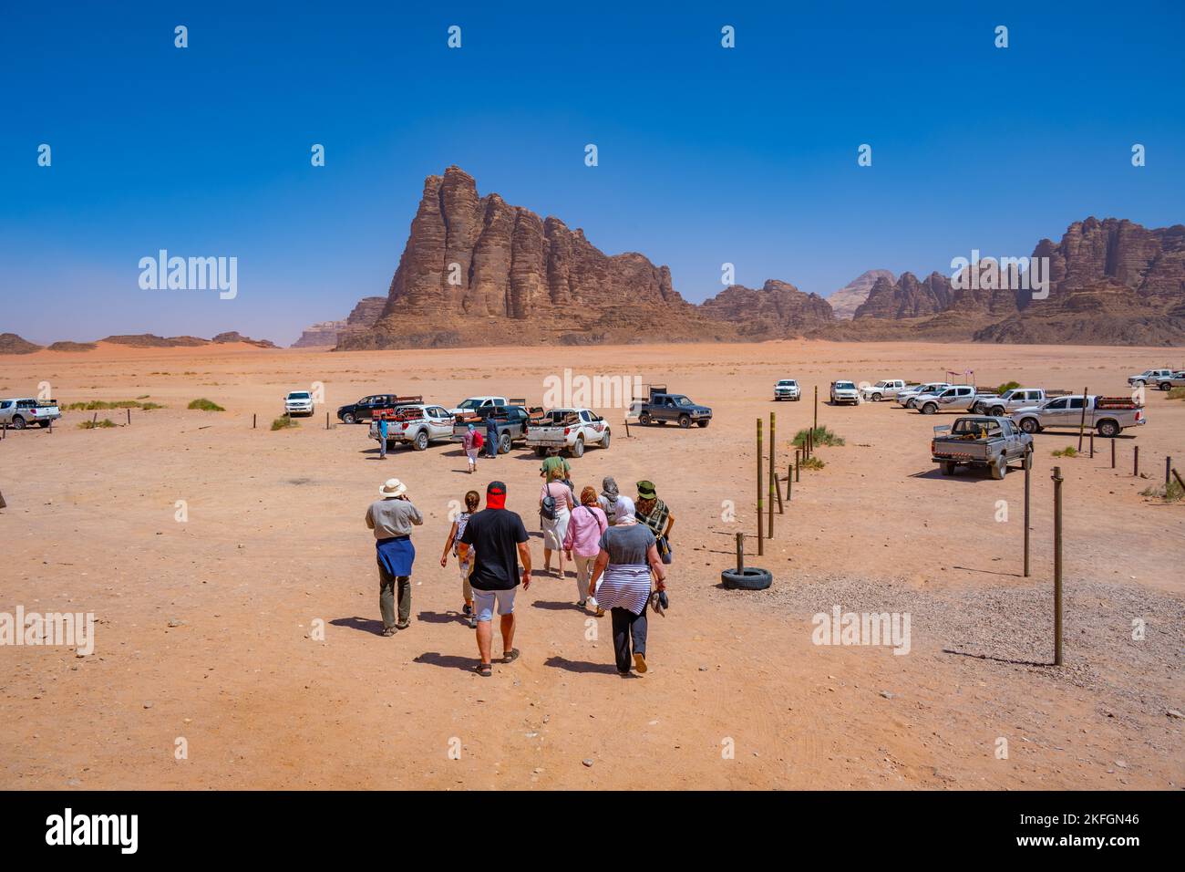 Tourists walking towards 4x4 transport at the Wadi Rum visitors centre and the Seven Pillars of Wisdom Mountain Stock Photo