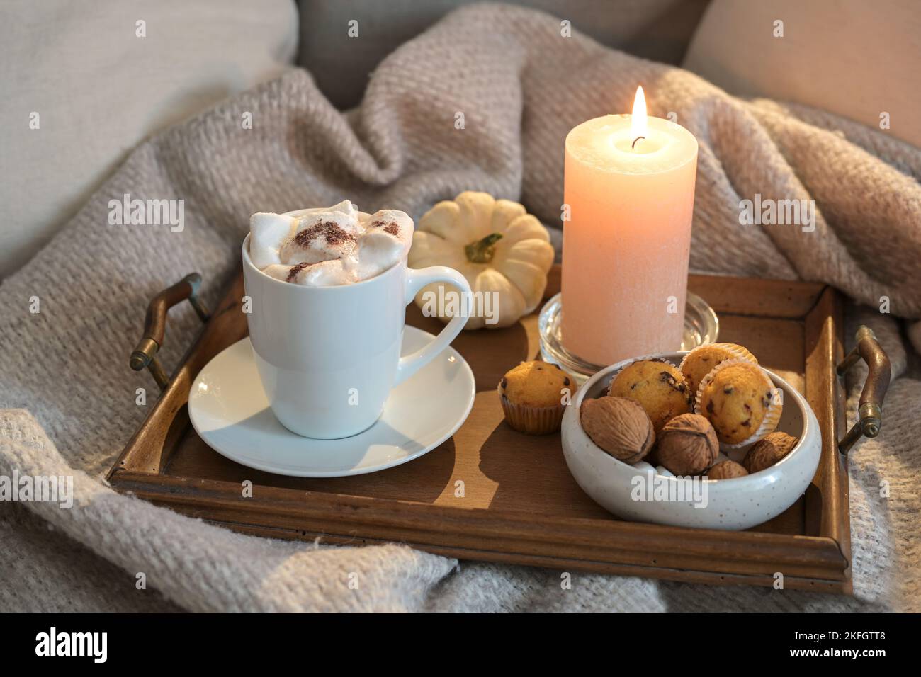 Cozy relaxation at home in autumn or winter time, chocolate hot drink and melting marshmallows, muffins and a candle on the couch, copy space, selecte Stock Photo