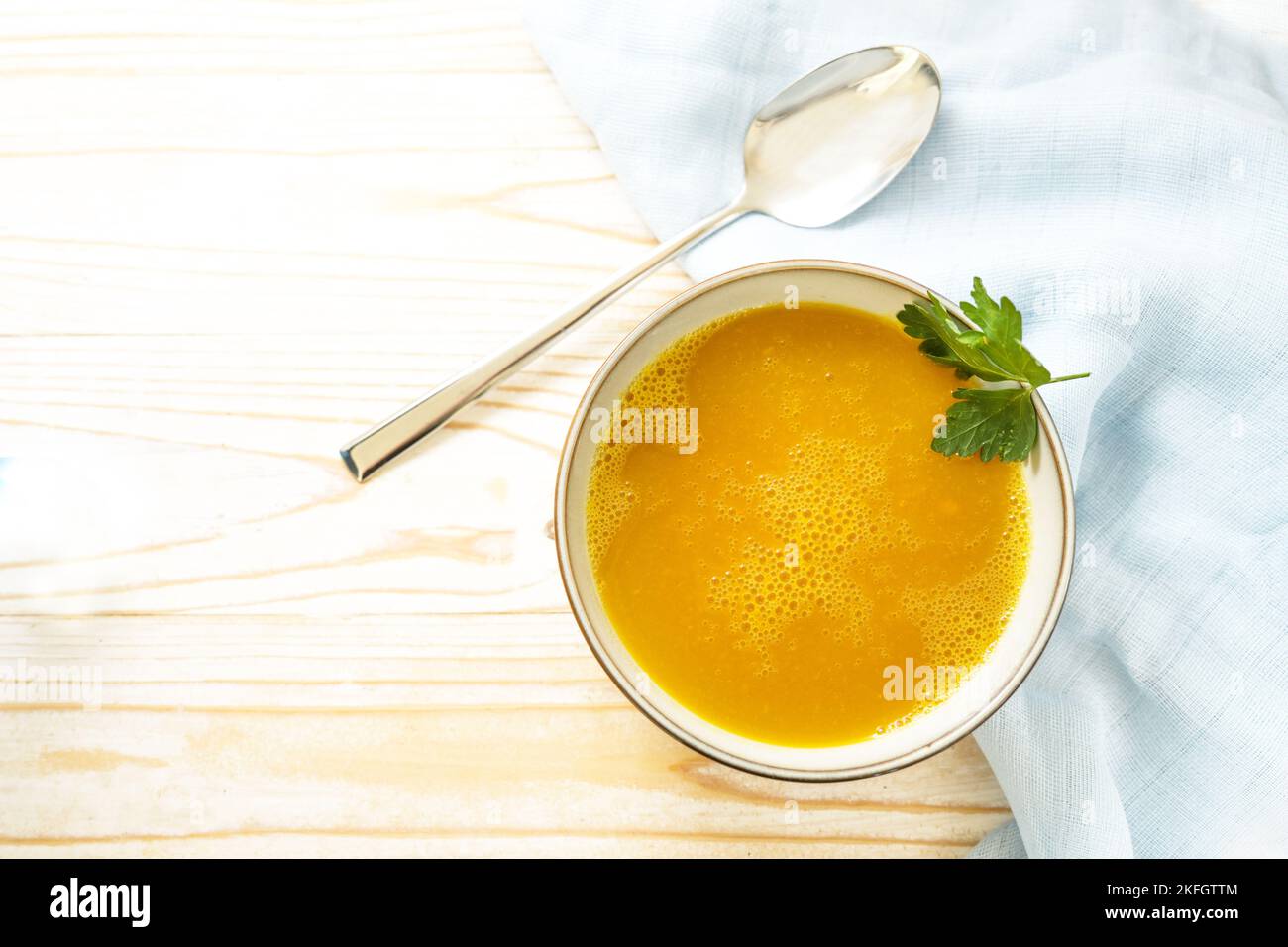 Carrot soup in a bowl on a light wooden table, healthy vegetable meal, recipe by professor Ernst Moro against diarrhea, copy space, high angle view fr Stock Photo