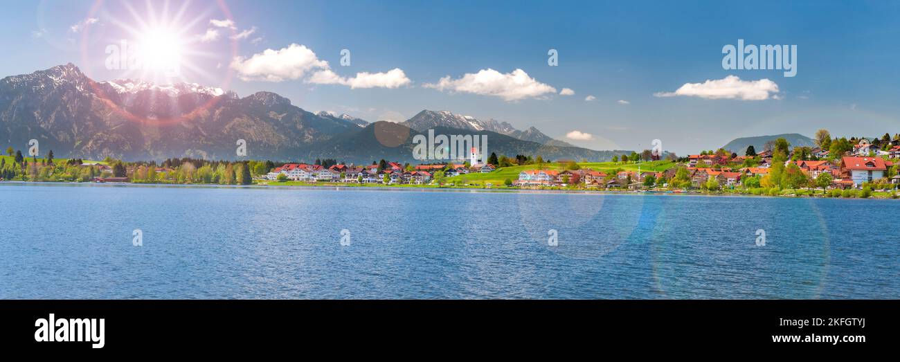 panoramic landscape with lake, mountain range and sun on sky Stock Photo