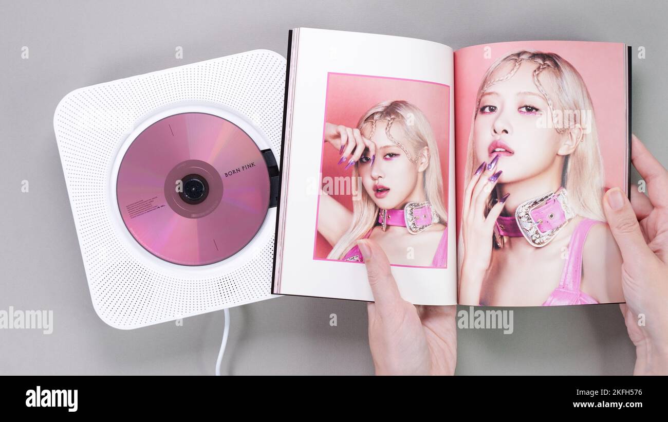 Fan hands holding BlackPink BORN PINK 2nd Album photobook with Rose on grey. Pink music CD in player. South Korean girl group BlackPink. Space for Stock Photo