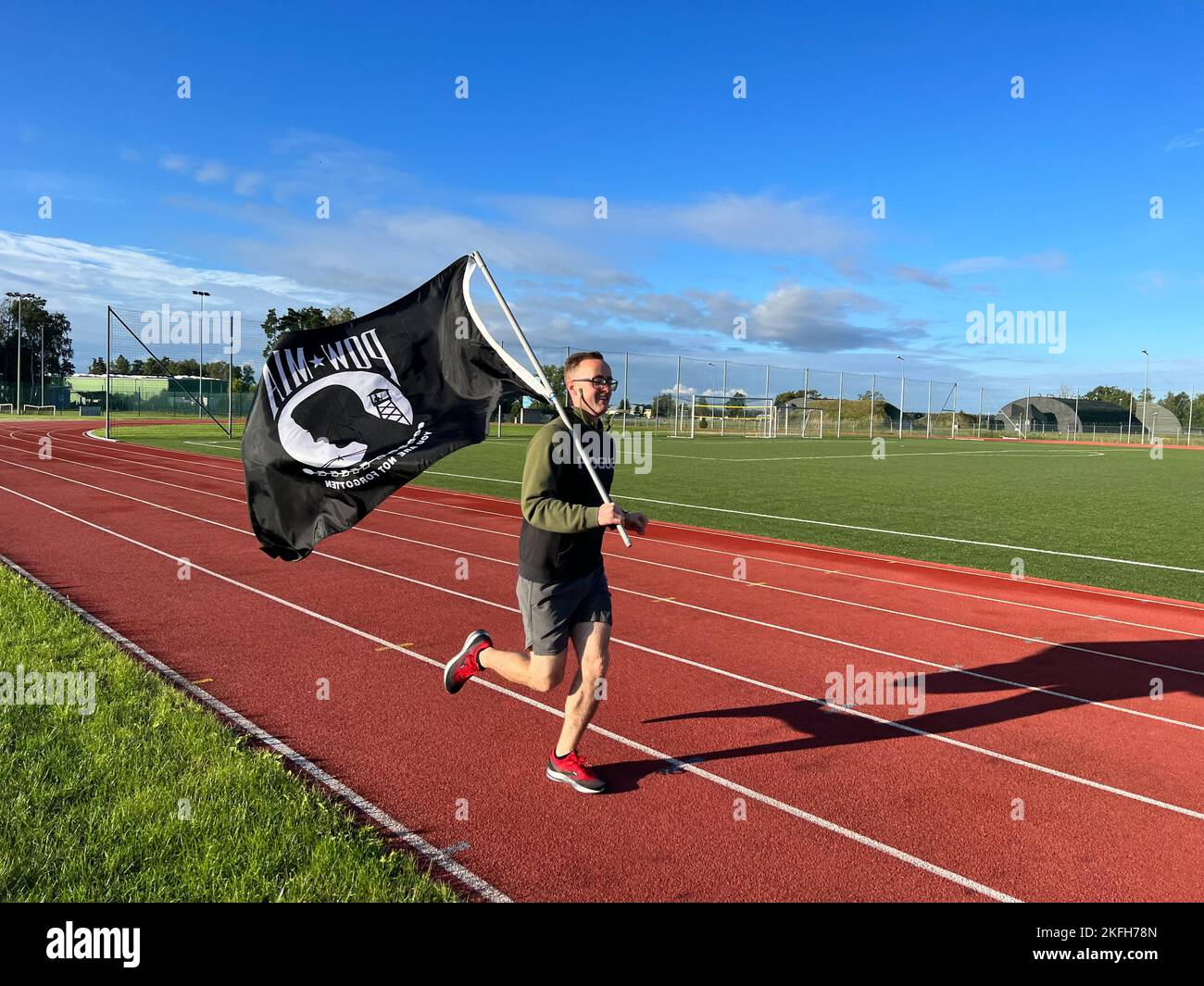 A member of the 90th Expeditionary Fighter Squadron runs while carrying the Prisoner of War/Missing in Action (POW/MIA) flag during a 24 hour remembrance run for those who were prisoners of war and those who are still missing in action, Sept. 16, 2022 at Łask Air Base, Poland. The 90th EFS forward deployed to Poland in support of NATO’s Air Shielding mission to enhance the defense posture on NATO’s eastern flank. 43 men and women of the 90th carried the flag for more than 160 miles over the 24 hour period to demonstrate that the American prisoners of war and missing in action are not forgotten Stock Photo