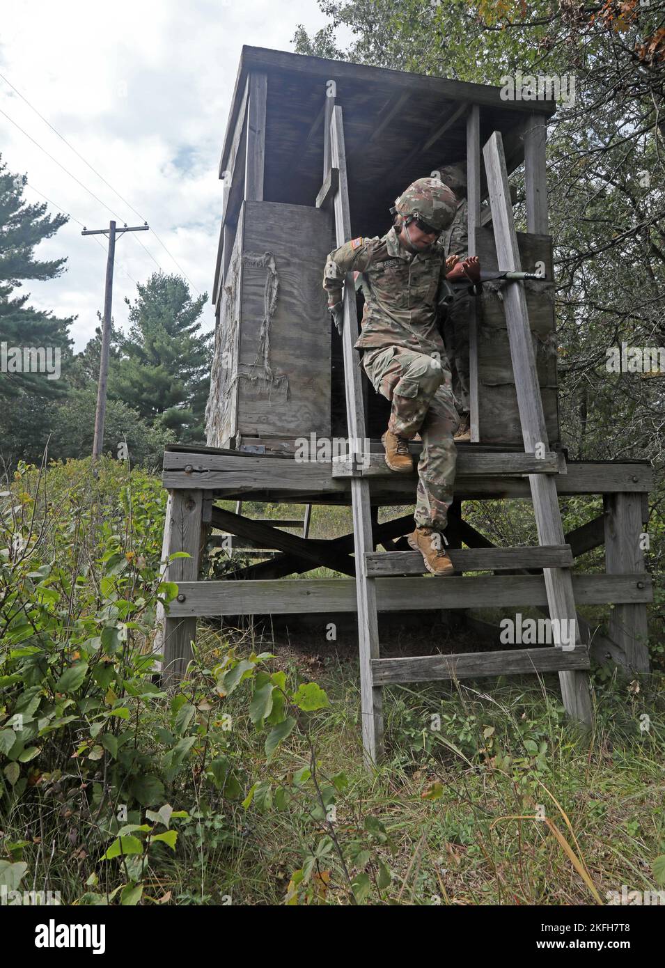 U.S. Army Reserve Spc. Ashley Carson, assigned to the 452nd Combat Support Hospital, 807th Medical Command (Deployment Support) based in Milwaukee, grabs a guard shack ladder rail as she carefully steps on the ladder rungs while holding a collapsible litter carrying a 'casualty' held by two other Soldiers during a litter obstacle course on Fort McCoy, Wis., Sept. 16, 2022. Stock Photo