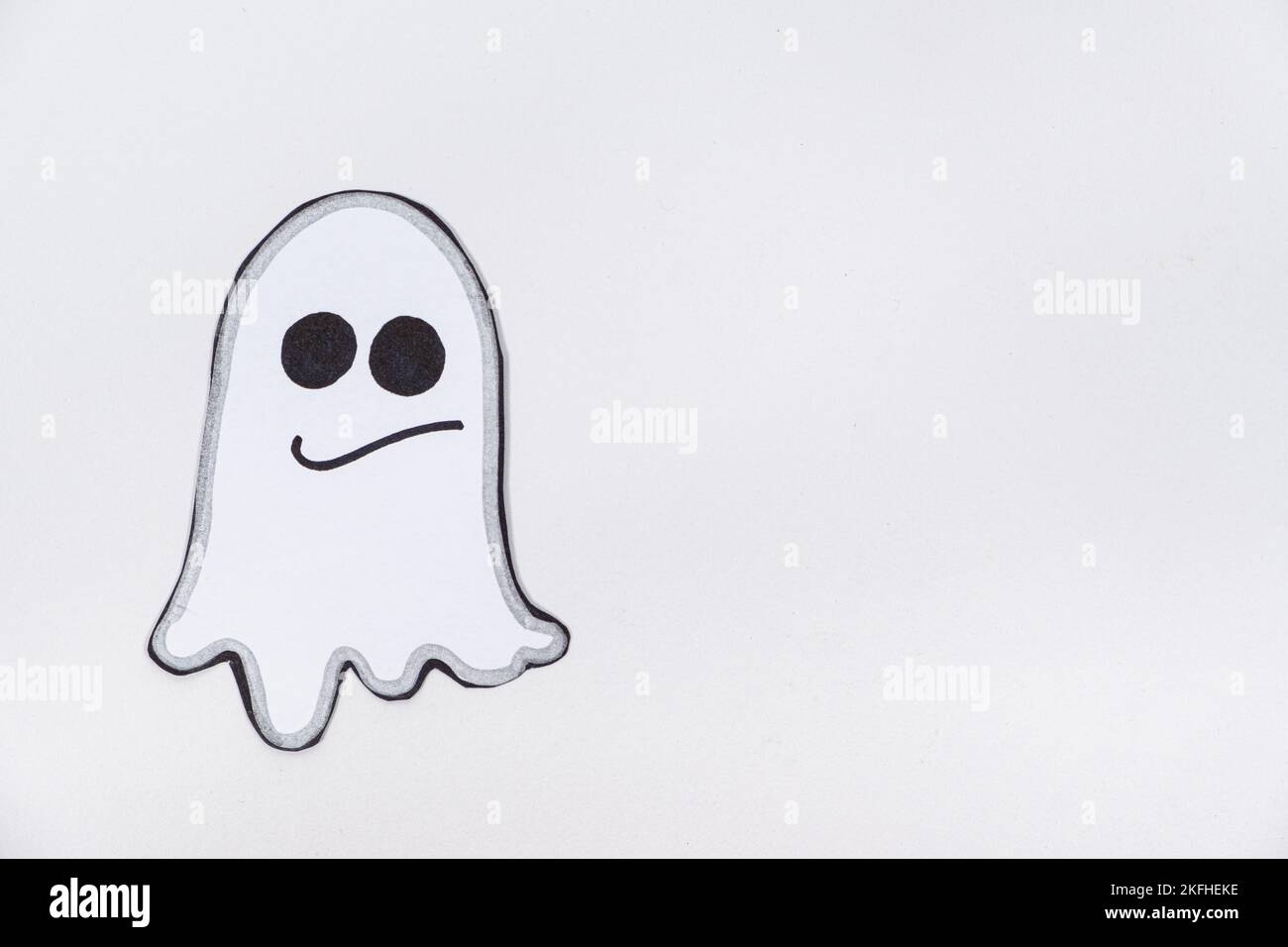 Funny paper ghost with eyes and mouth smiling on a white background, top view Stock Photo