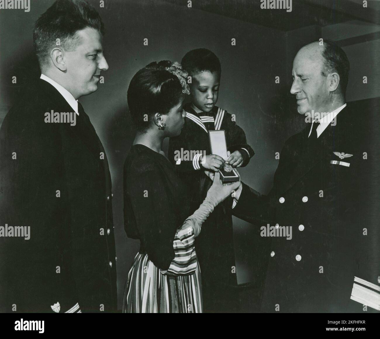 Mrs. Charles W. David, Jr.; African American widow and her three-year-old son, Neil Adrian receiving the Navy and Marine Corps Medal from Rear Admiral, Stanley V. Parker, 1939 - 1945. Stock Photo
