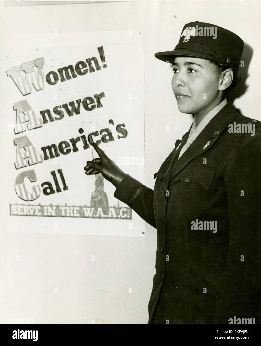 African American Charity Adams, First Officer in the Women's Army Auxiliary Corps, standing in uniform and pointing to a poster that reads, &quot;Women! Answer America's Call, Serve in the W.A.A.C.&quot;,  1943-02. Stock Photo