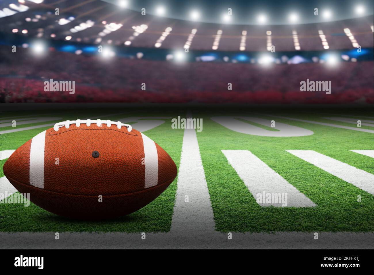 American football on field in stadium with dramatic spot lighting and copy space. Focus on foreground ball with shallow depth of field on background. Stock Photo