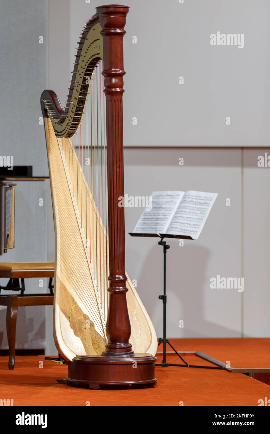 a concert harp stands next to a music stand Stock Photo