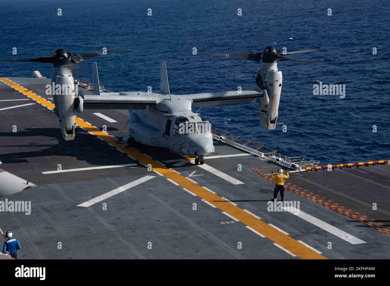 EAST CHINA SEA (Sept. 17, 2022) Aviation Boatswain’s Mate (Handling) 3rd Class Joseph Barrios, from Miami, assigned of the forward-deployed amphibious assault carrier USS America (LHA 6), signals an MV-22B Osprey tiltrotor aircraft from the “Flying Tigers” of Marine Medium Tiltrotor Squadron (VMM) 262 to stand by on America’s flight deck during flight operations in the East China Sea, Sept. 17, 2022. America, lead ship of the America Amphibious Ready Group, is operating in the 7th Fleet area of operations to enhance interoperability with allies and partners and serve as a ready-response force Stock Photo