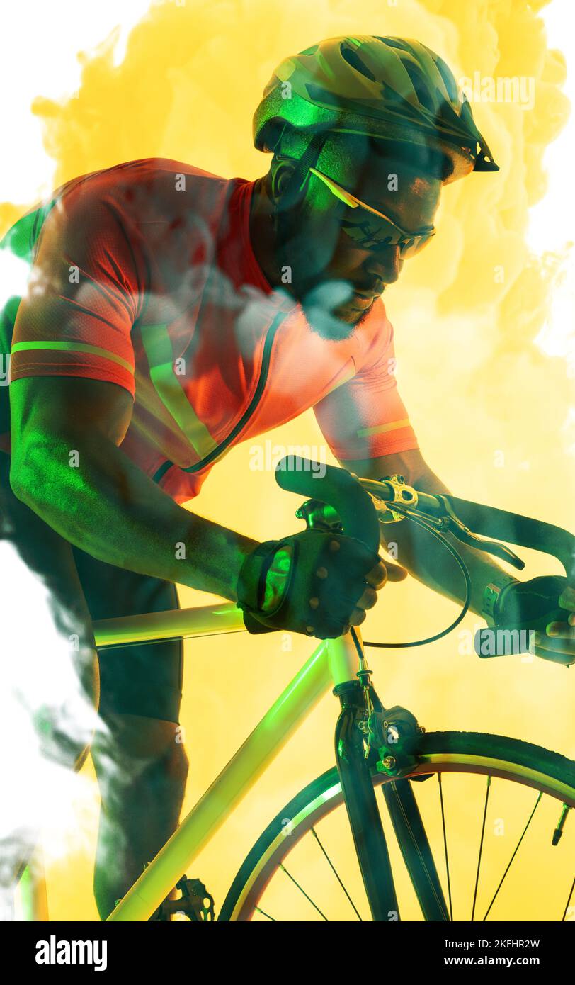 African american male cyclist wearing helmet and eyewear riding bike over yellow smoky background Stock Photo