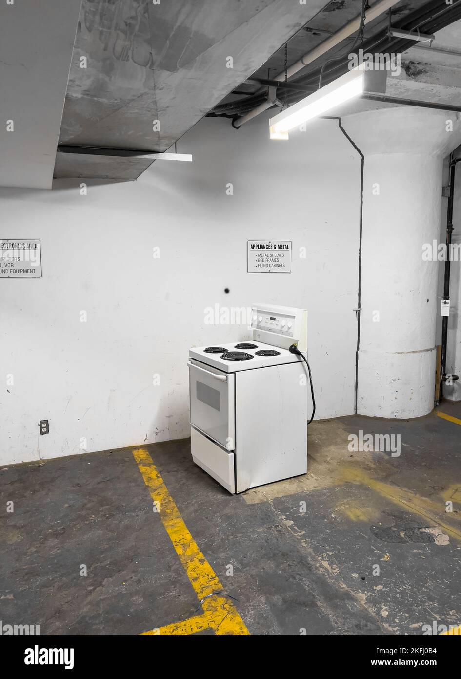 Metallic kitchen stove with oven against white wall in empty storage
