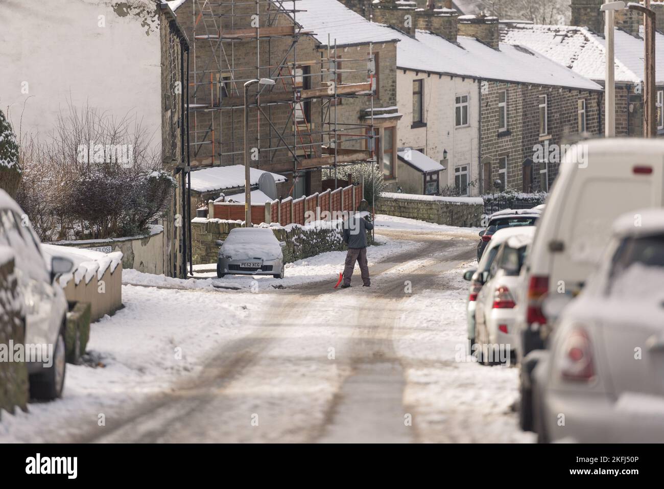 Snow covered street with cars parked by the side of the road. man ...