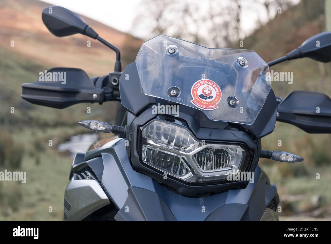 Close up view of the headlight and screen of a BMW F750GS. North West Bloodbikes Lancs and Lakes volunteer rider sticker on the screen. Stock Photo