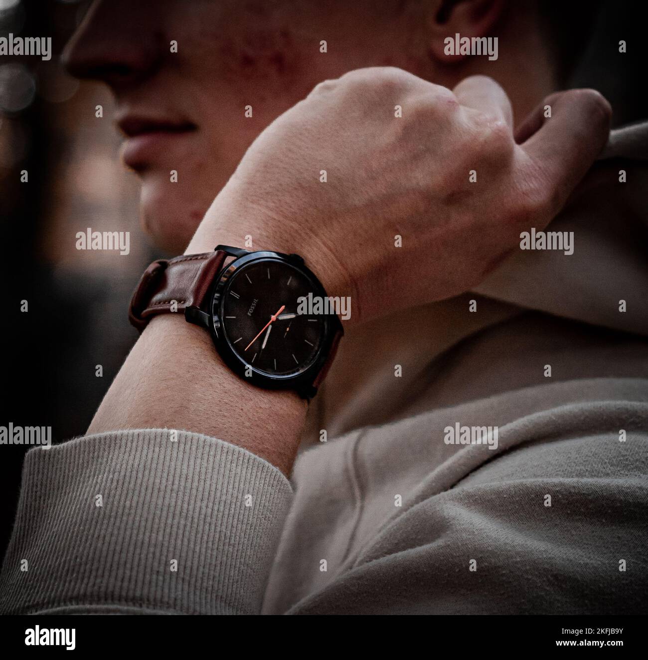 A man wearing a watch while adjusting his hood Stock Photo