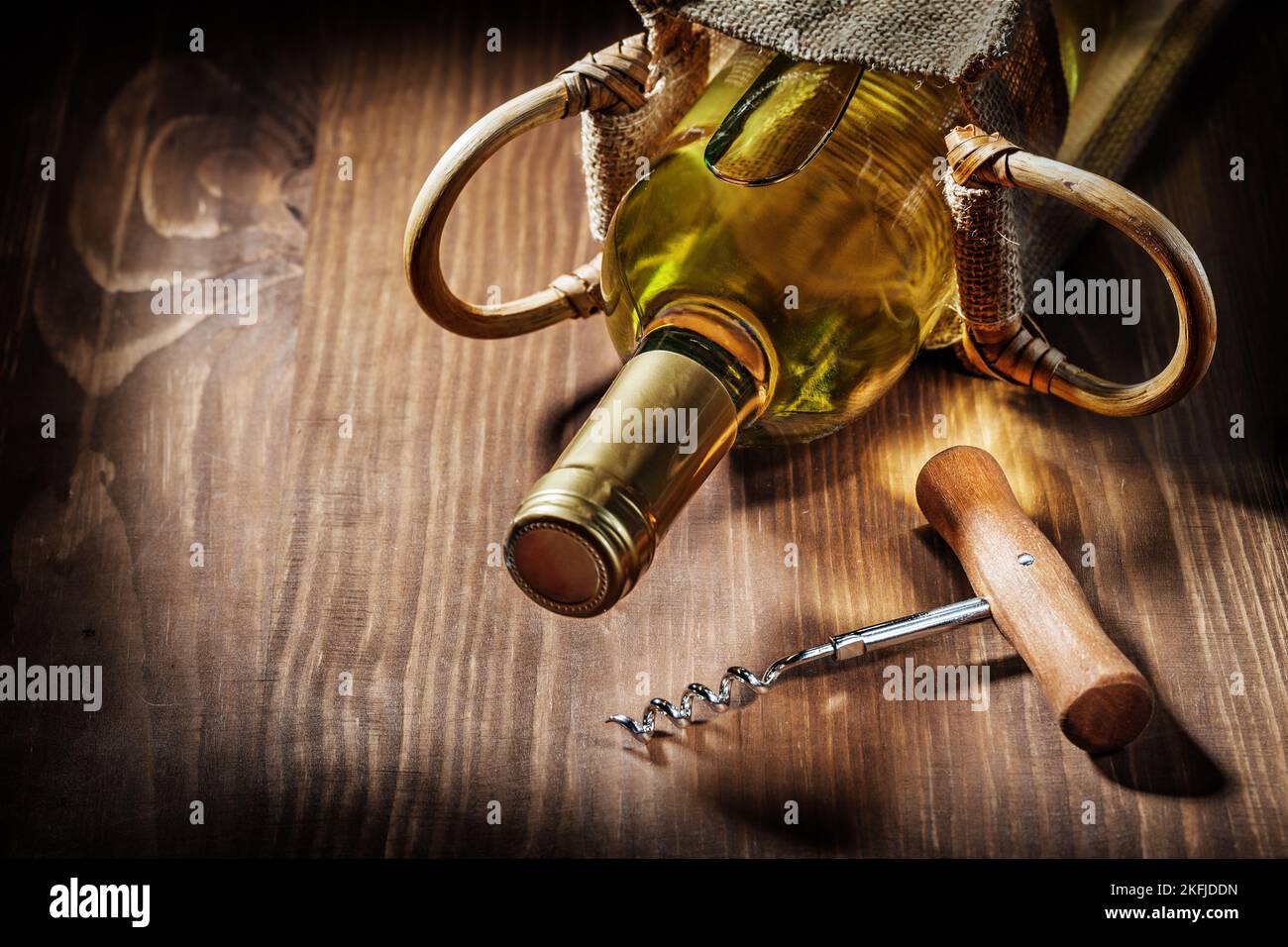 bottle of white wine in burlap bag and vintage corckscrew Stock Photo