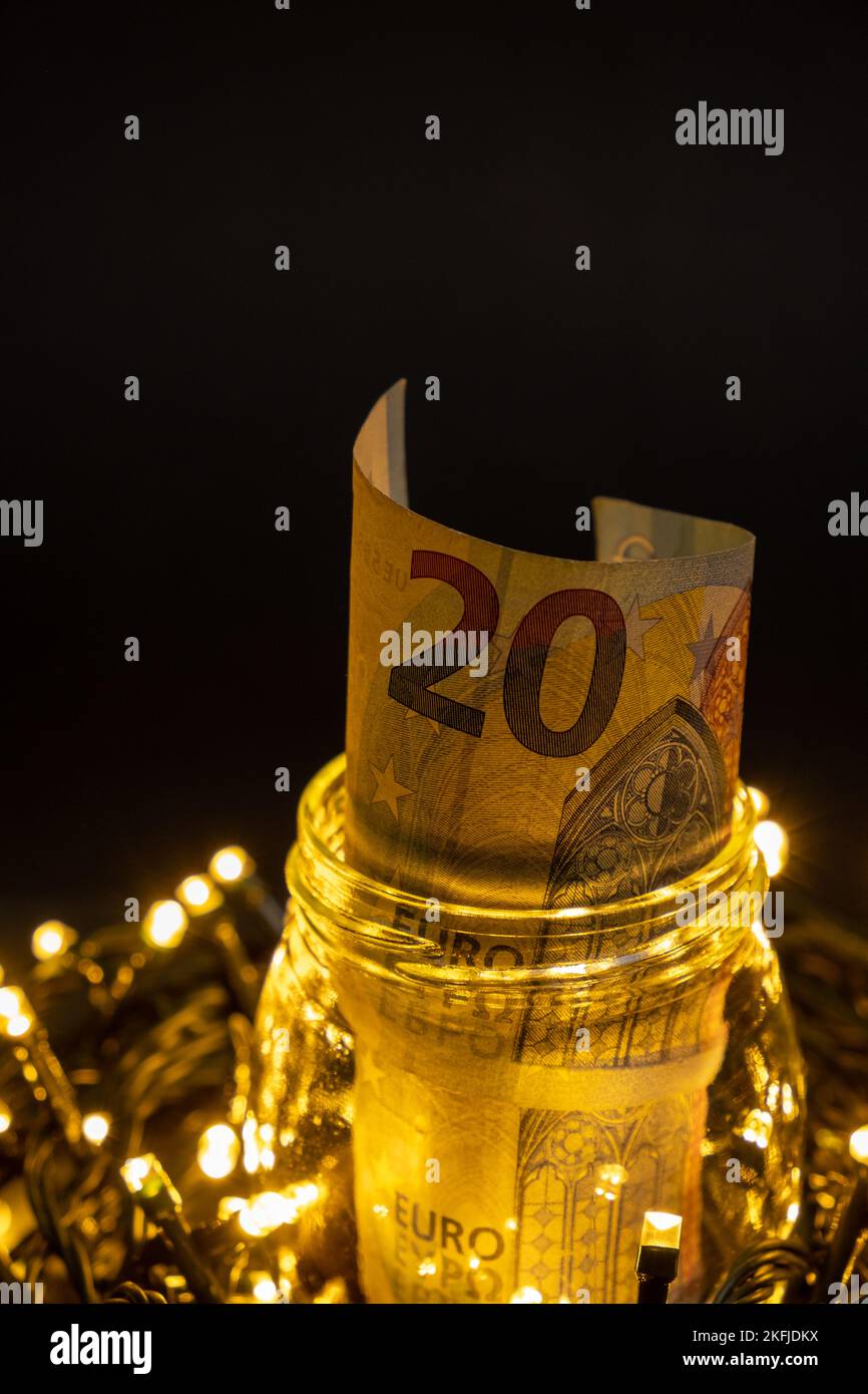 Glass jar with twenty euro banknote on a dark background on top of led