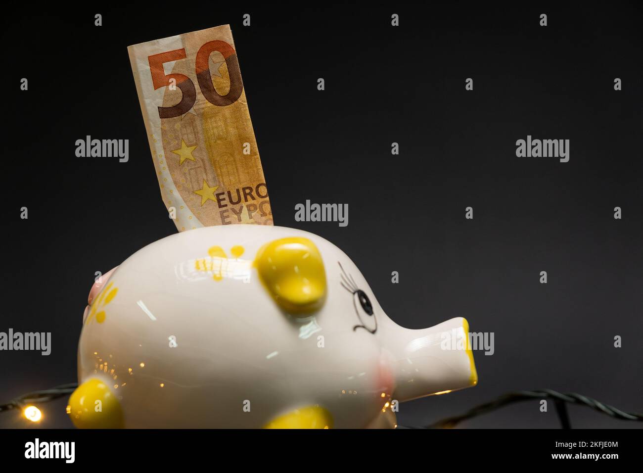 Fifty euro banknote in a piggy bank, on a dark background. Side view. Concept of saving money. copy space. Stock Photo