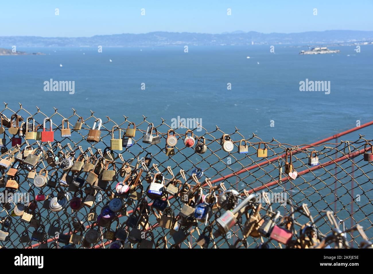 Close up of many lovelock padlocks placed by tourists on a chain link fence above the Golden Gate Bridge with the San Francisco bay in the background Stock Photo