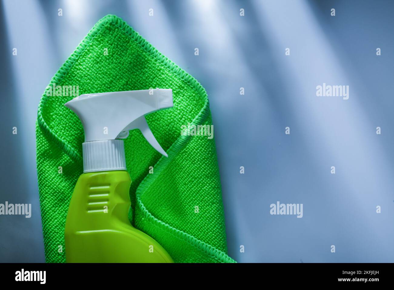 Green washing rag sprayer on white surface. Stock Photo