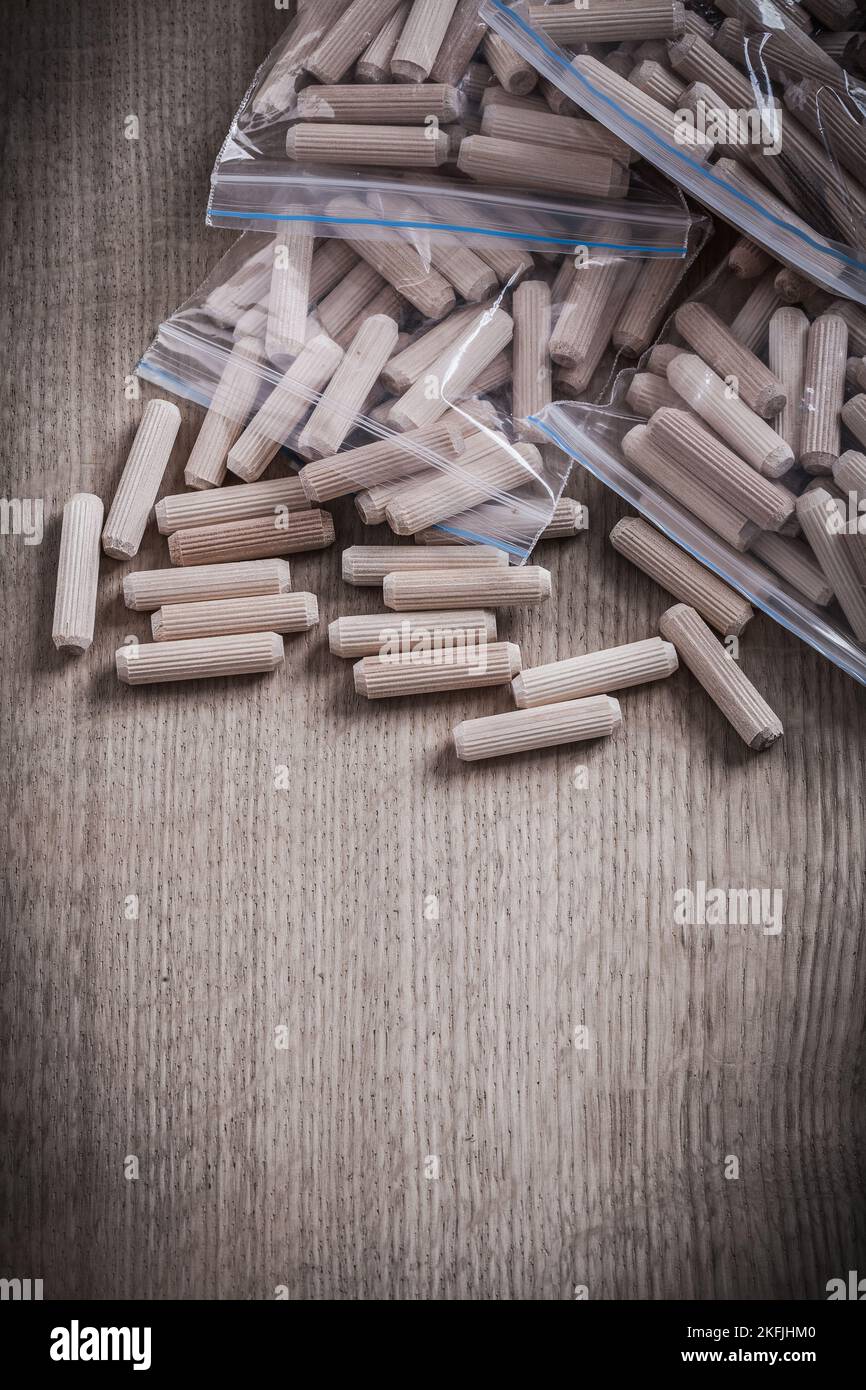 Wooden dowel pins on wood board vertical view construction concept