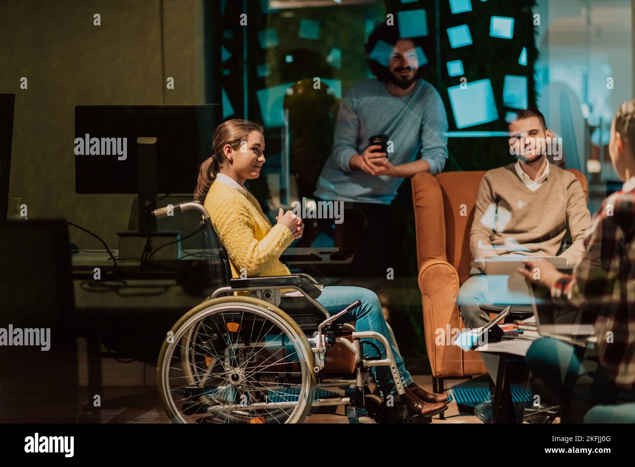 Businesswoman in wheelchair having business meeting with team at modern office. A group of young freelancers agree on new online business projects Stock Photo