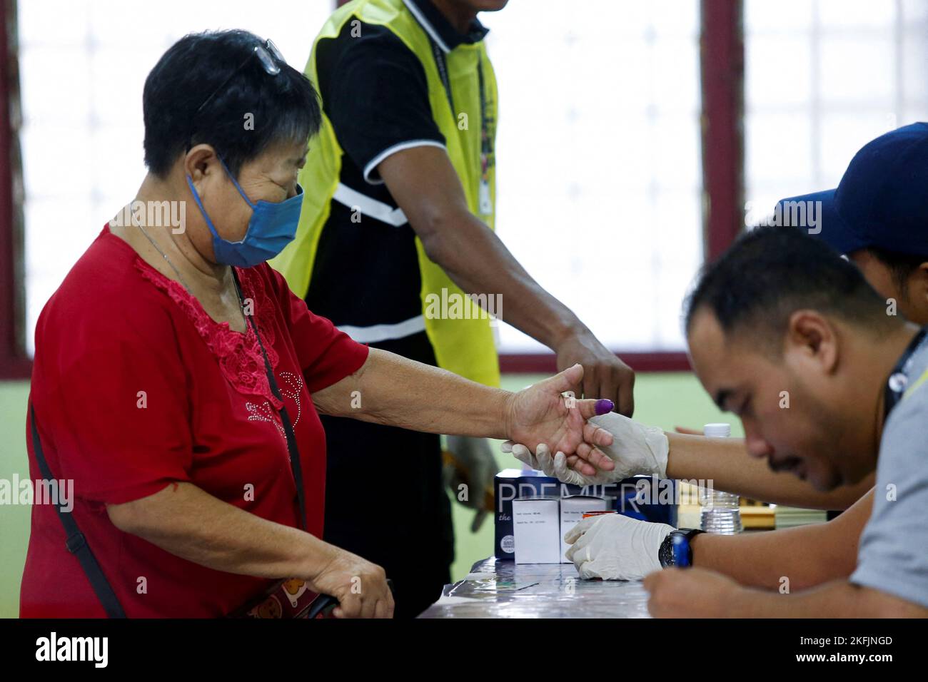 An election worker dips a voter's finger in ink, during Malaysia's 15th general election, in Bera, Pahang, Malaysia November 19, 2022. REUTERS/Lai Seng Sin Stock Photo