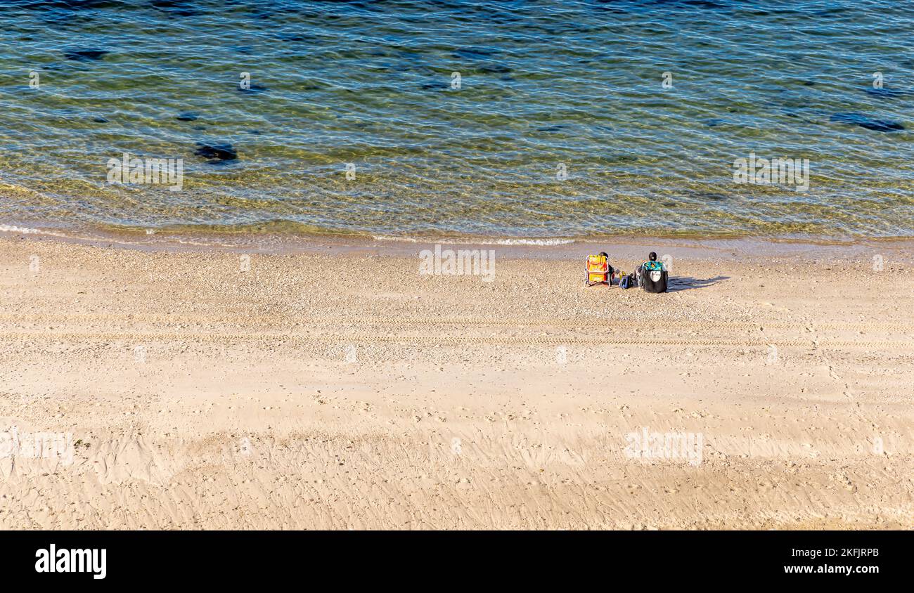 Couple sitting in beach chairs on a large beach on the north shore Stock Photo